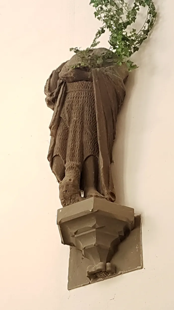 Die Sandsteinfigur Johannes des Täufers heute, auf einer Konsole an der Wand.