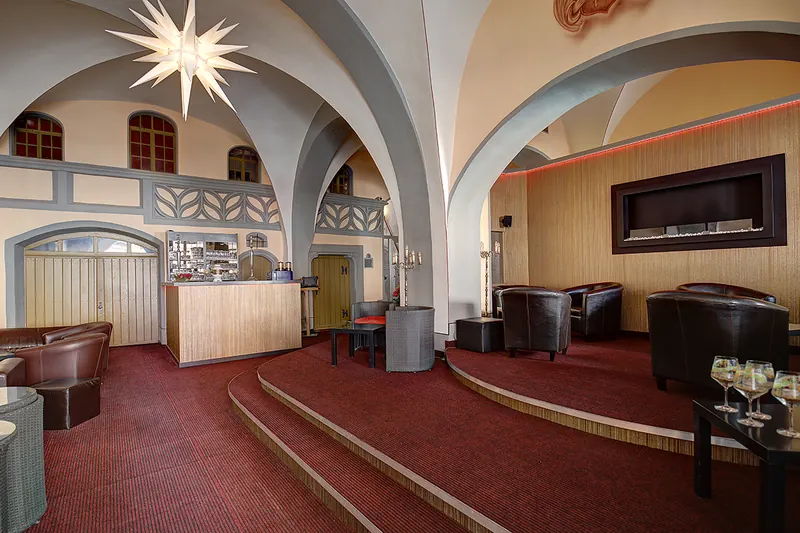 La sala del pianterreno oggi come bar: volte, una lampada a forma di stella, tappeti rossi e poltrone.