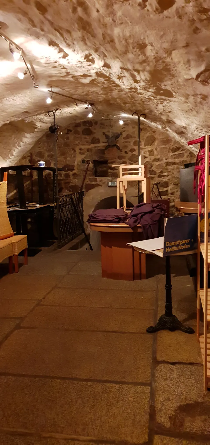 Cantina a volta in pietrame sotto la sala centrale, con pavimento in pietra e alcuni mobili.