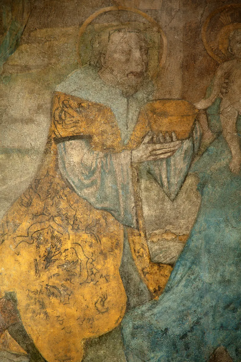 Pittura murale: il re inginocchiato in veste gialla con l’aureola, tra le mani un vaso d’oro.