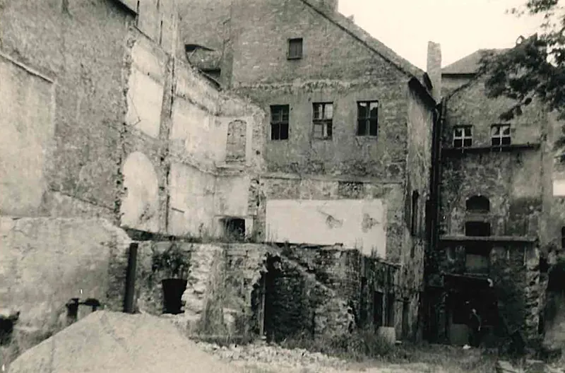 Foto in bianco e nero del 1965: il cortile pieno di macerie, edifici posteriori crollati, muri aperti.
