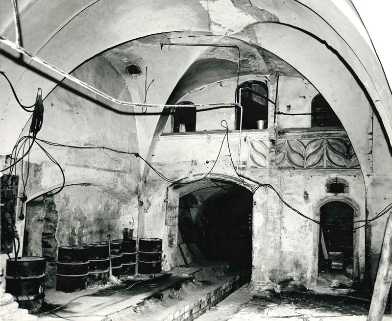 Foto in bianco e nero del 1974: la sala del pianterreno durante i lavori, volte e archi, materiali da costruzione sul pavimento.