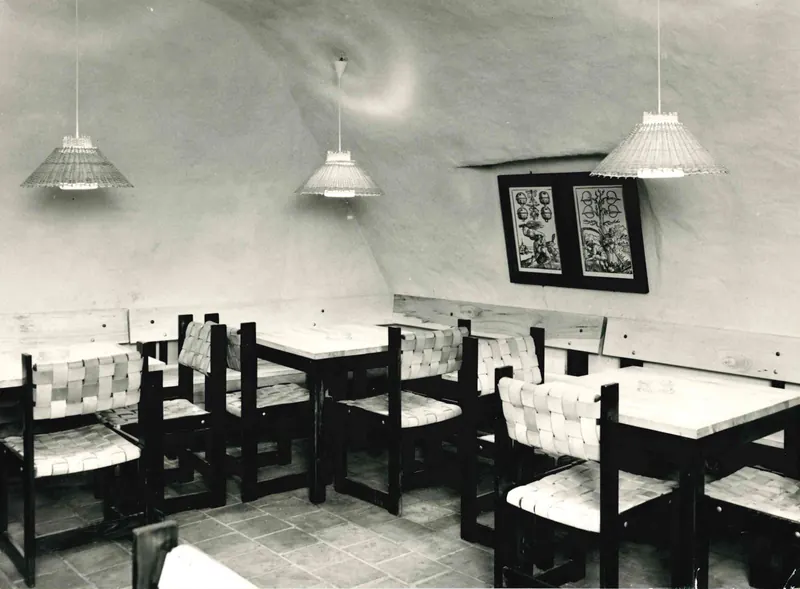 Foto in bianco e nero del 1976: una cantina a volta imbiancata con tavoli e sedie del ristorante.