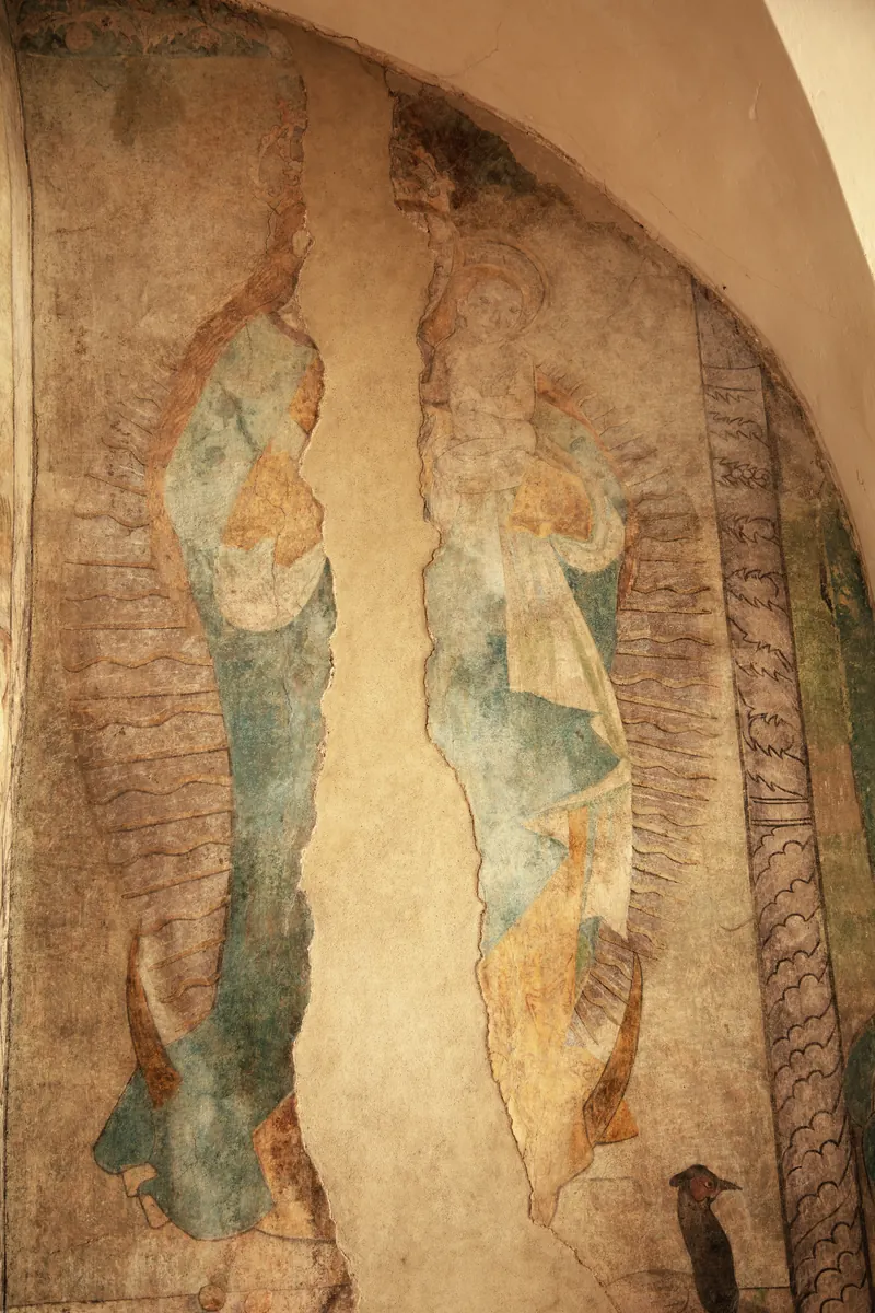 Pittura murale sbiadita su un pilastro: i contorni di Maria con il Bambino sopra una falce di luna.